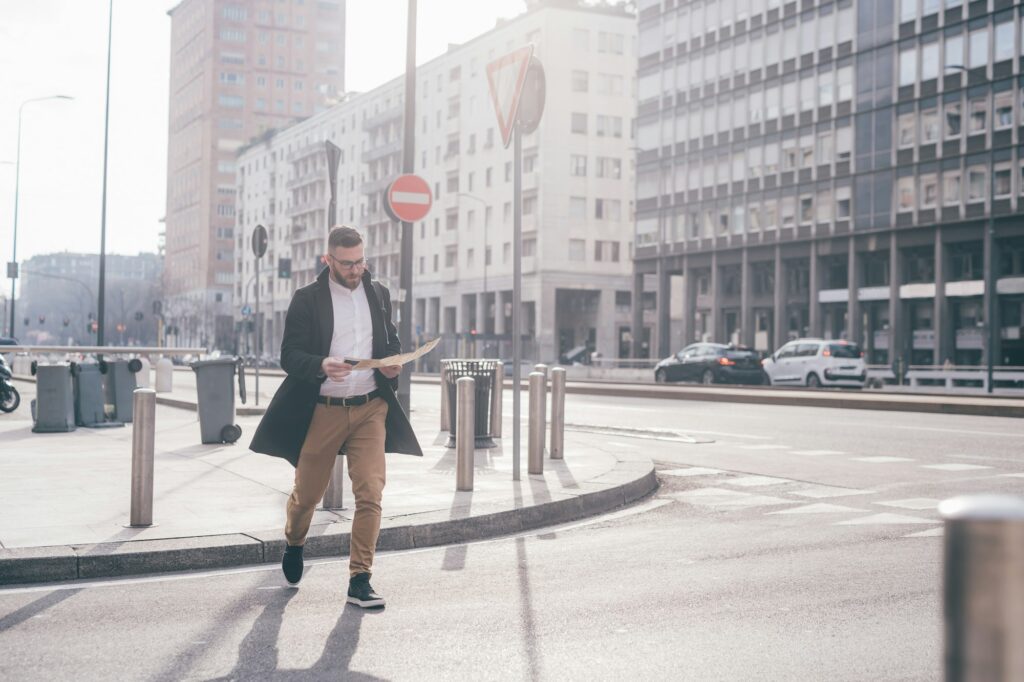 Young bearded caucasian traveller checking guide map and smartphone